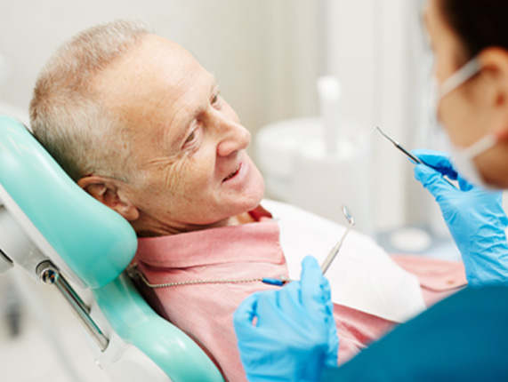 Older man in treatment chair seeing dentist