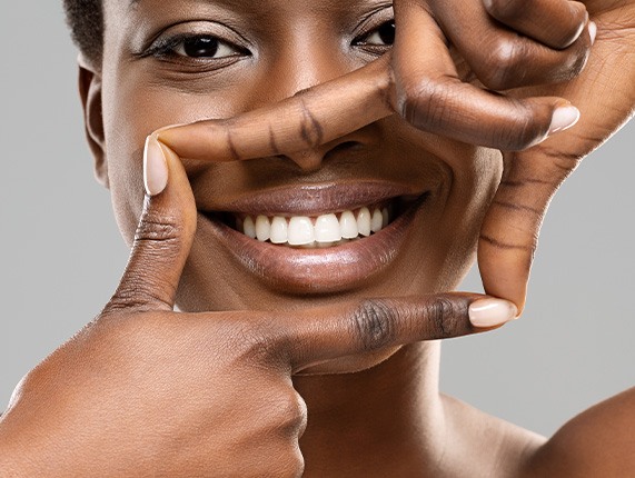 Woman framing her smile with four fingers