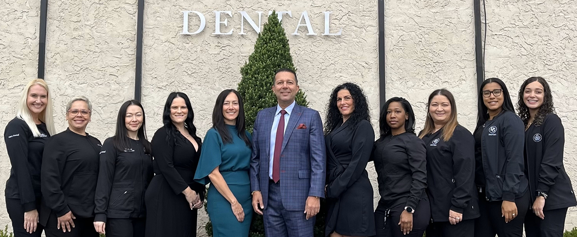 West Orange dental team standing in a line in black scrubs with their arms crossed