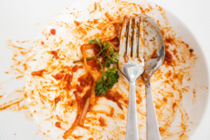 A messy plate of leftover pasta covered in tomato sauce